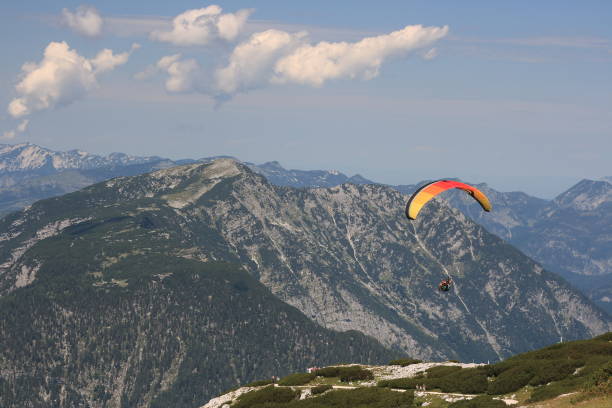 istock Alps. Dachstein Mountains. Austria. Paraplaner gliding in blue sky with view on Alpine mountains on paraplane 1693545324
