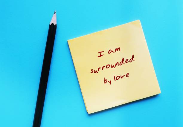 istock Stick note on blue background with handwritten text - I am surrounded by love - positive affirmation to boost self esteem in daily life 1693565648