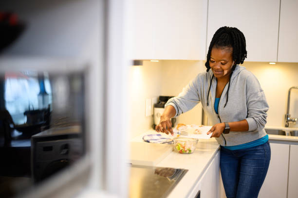 istock Young woman adding chicken to salad in kitchen 1693568874