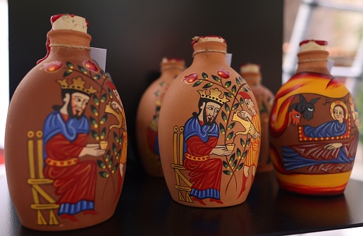 A grouping of three hand-painted glass bottles in varying colors, sizes, and designs are displayed side-by-side on a smooth wooden surface