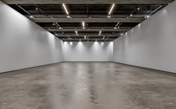 istock Front view of an empty white large gallery/showroom interior with white partition empty walls for events or artwork exposure, and a ceiling industrial construction with reflectors (lights) 1693585062