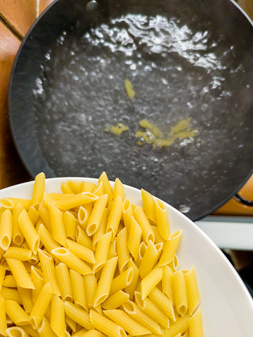 Pouring Penne Pasta into the Boiling Water
