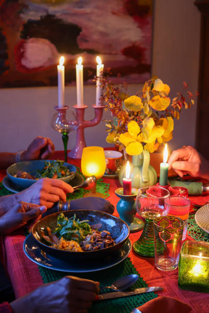 Artistic autumn tablescape: porcelain, candlelight, and diners' hands.
