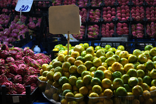Fruit stall in the market. Tangerines and dragon fruits. Blank price tag. Partial lighting.