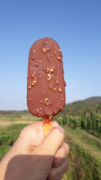 istock Sweet chocolate ice cream on hand with blue sky view 1693661788