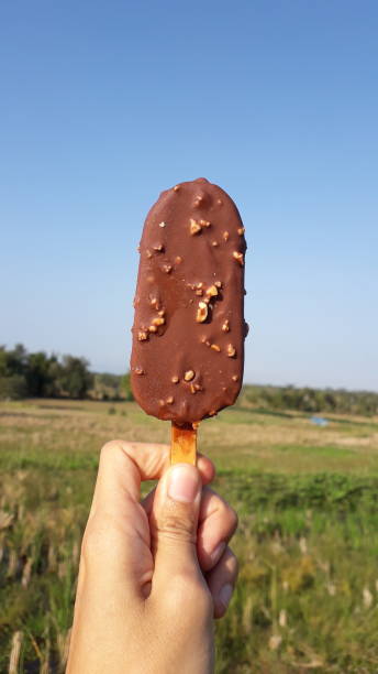 istock Sweet chocolate ice cream on hand with blue sky view 1693661812