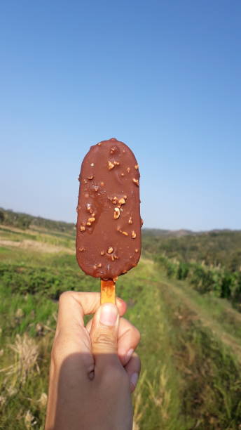 istock Sweet chocolate ice cream on hand with blue sky view 1693661819