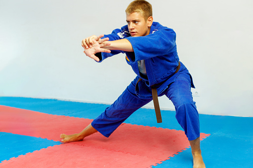 A teenager does warm up exercises before aikido training.