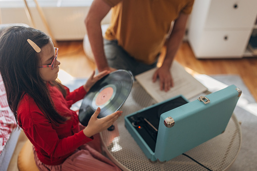 Father and daughter listening to vinyl records on gramophone