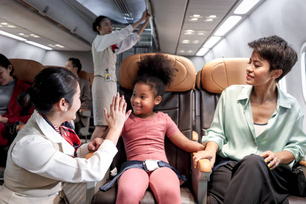 istock Friendly air hostess take care and help kid passenger on airplane, cheerful flight attendant and curly hair African girl giving high five on aircraft, child traveling by plane, airline transportation 1693741762