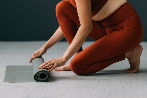 In a moment of tranquility, a woman unfurls her yoga mat, setting the stage for a rejuvenating yoga class that promises inner peace and wellness.