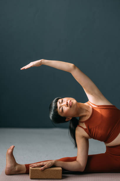 istock Asian Woman Using a Yoga Block for Support While Exercising 1693747499