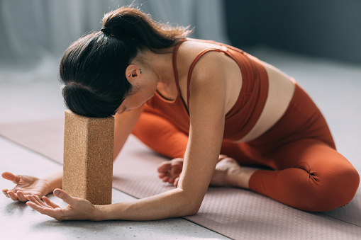 Asian Woman Using a Yoga Block for Support While Exercising