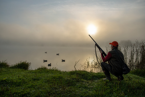 Duck hunter on the lake at sunrise. Hunting season.