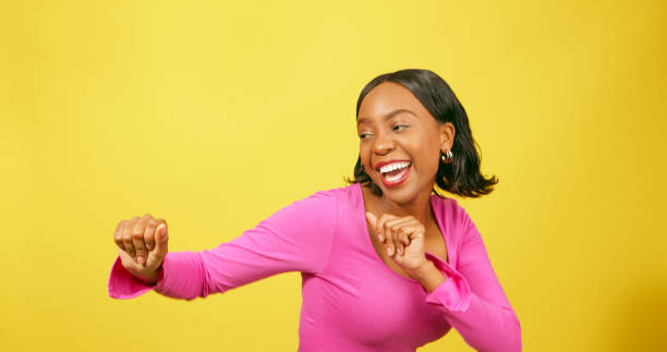 istock Happy young woman dancing, having fun, yellow studio background 1693775973
