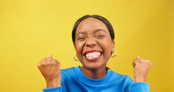 Excited woman cheers, winning happy dance, yellow studio background. High quality photo