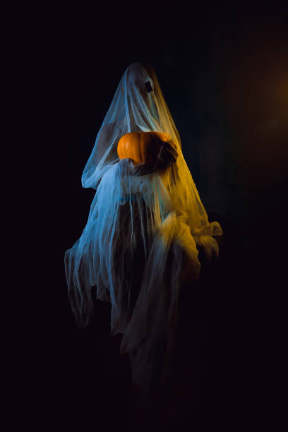 istock Halloween pumpkin in a ghost costume on a dark background with light. Halloween 1693777212