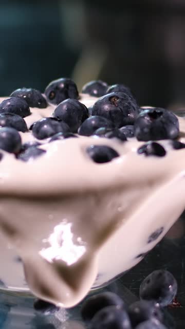 pour blueberries in a glass plate with thick sour cream next to peaches and apricots Yogurt with blueberry Tasty liquid Texture of white sour cream with blueberry. Creamy dairy product.
