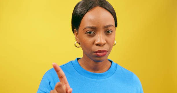istock Beautiful strong woman gestures No with finger, shakes head, yellow studio 1693792507