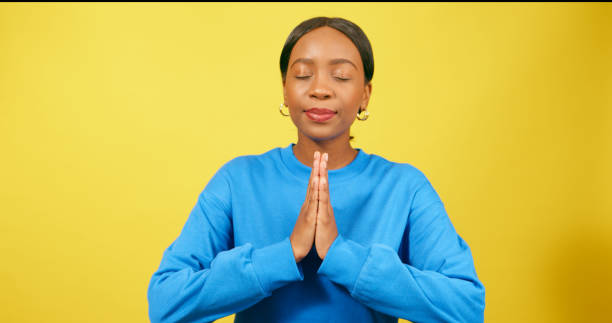 istock Calm young woman puts hands into prayer position, praying, yellow studio 1693793042