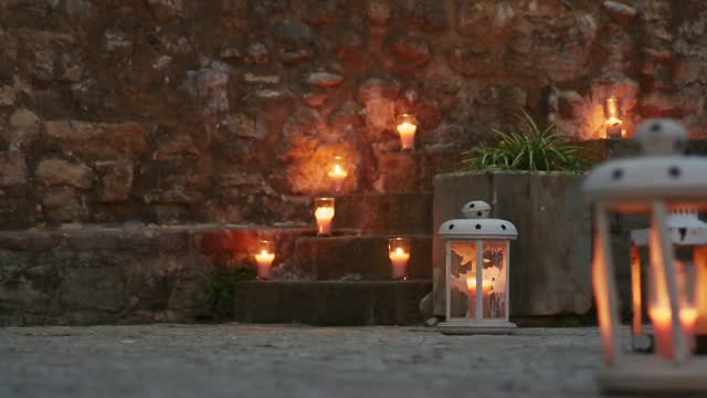 Burning candles placed on the steps of the stairs of a European old town. Wedding or reception decoration during blue twilight or evening.