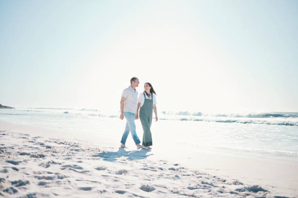 istock Beach, happy couple or walking while holding hands on vacation, care or bonding in summer mockup space. Man, woman or smile at ocean to travel, romance or support love in relationship together at sea 1693814487
