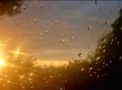 Raindrops reflecting sunlight on a window at day end