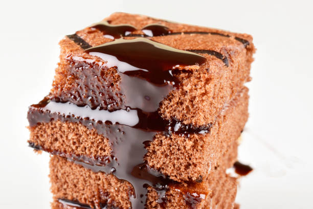 istock Piece of chocolate cake dripping with chocolate syrup isolated on white background 1693856557