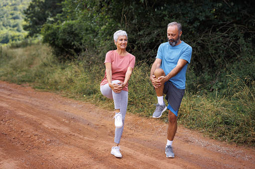 Mature couple  performing warm up exercise prior to exercising in the park