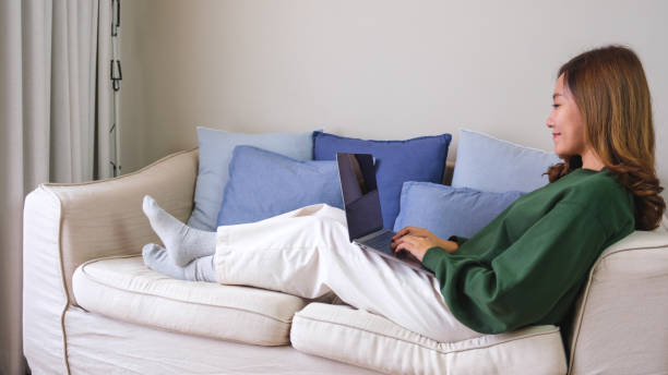 istock A woman using and working on laptop computer while laying down on a sofa at home 1693857124
