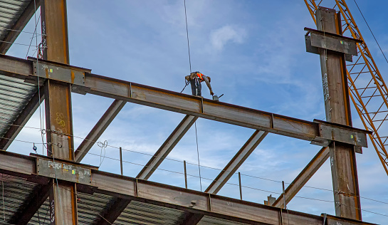 Iron worker standing on the edge of a high steel beam at a construction site