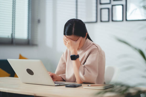 istock Asian woman suffering from headache sitting at home office. 1693863254