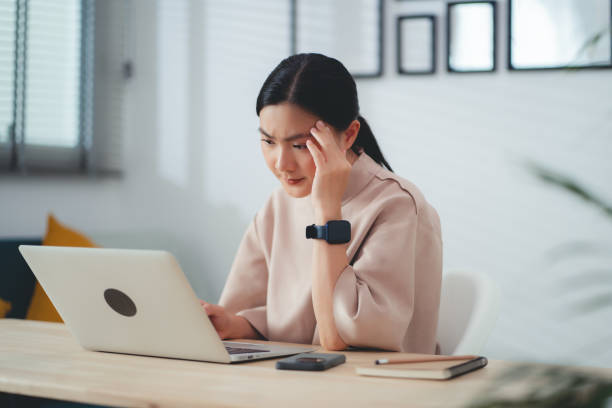 istock Asian woman suffering from headache sitting at home office. 1693863263