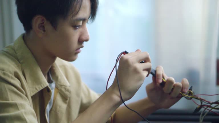 Asian students using measurements repairing electronic pc hardware in the classroom.