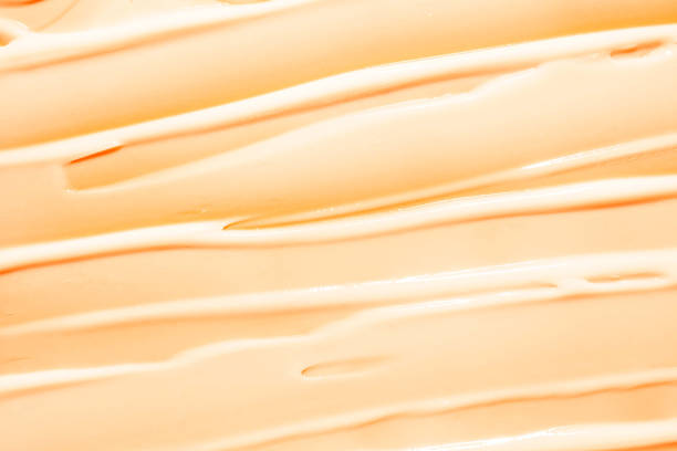 istock Orange and white cosmetic mask or cleansing foam swatch smudge texture background 1693868480