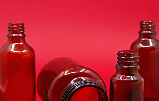 empty glass medicine bottle on red background