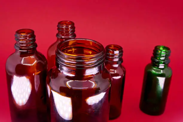 Photo of empty glass medicine bottle on red background