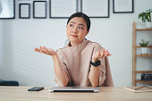 Asian woman thinking about project and feel confused sitting at home office.