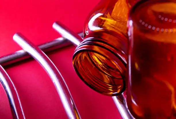 Photo of empty glass medicine bottle on red background