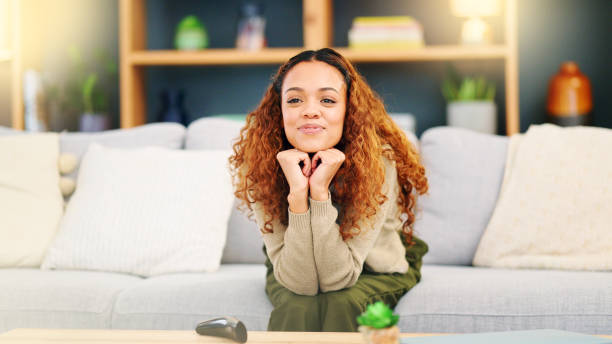 istock Lady laughing at comedy movie on her online subscription via wifi while sitting on her sofa at home. Young woman switches on tv using remote and enjoys stand up comedy relaxing on the couch indoors 1693883383