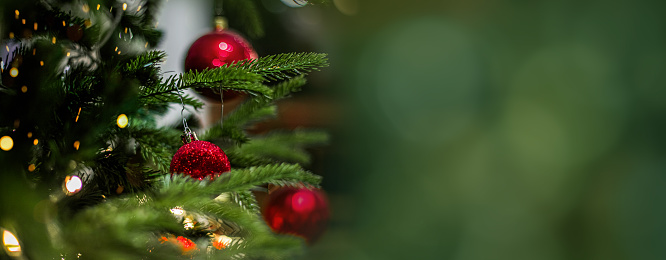 Seamless panoramic banner with Christmas composition of Christmas festive baubles and branches of fir tree on a beige background. Defocused lights on background. Copy space.