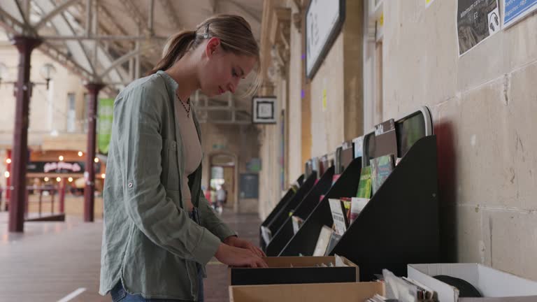 Teenage girl browsing vinyl records in a charity shop street stands.