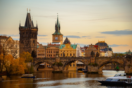 landscape with Vltava river, Charles Bridge and boat in the evening in autumn in Prague, Czech Republic.