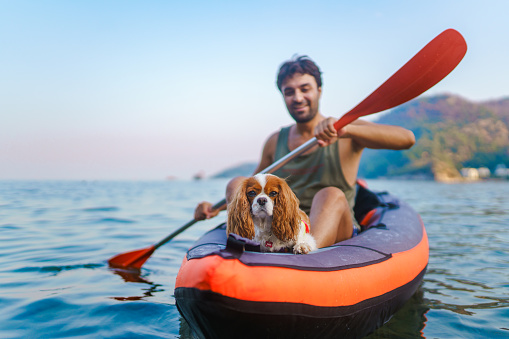 Adult man enjoys canoeing with his dog