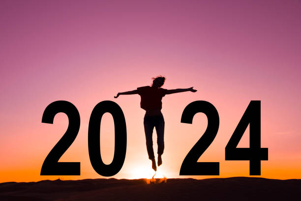 2024, silhouette of a woman jumping in the sun, joy and happiness, pink sunset sky stock photo