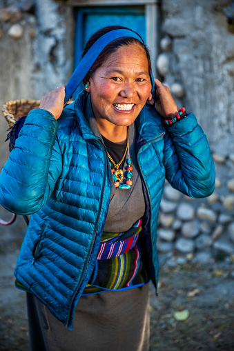 Tibetan woman carrying basket, small village in Upper Mustang. Mustang region is the former Kingdom of Lo and now part of Nepal,  in the north-central part of that country, bordering the People's Republic of China on the Tibetan plateau between the Nepalese provinces of Dolpo and Manang.