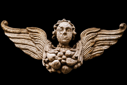 An angel with wings. Vintage ancient stone statue isolated on black background. Fragment.