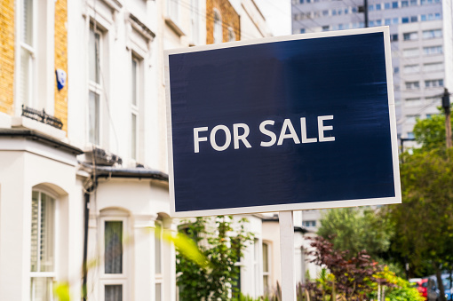 Close-up of a blue 'For Sale' real estate agent's sign in Islington, London.
