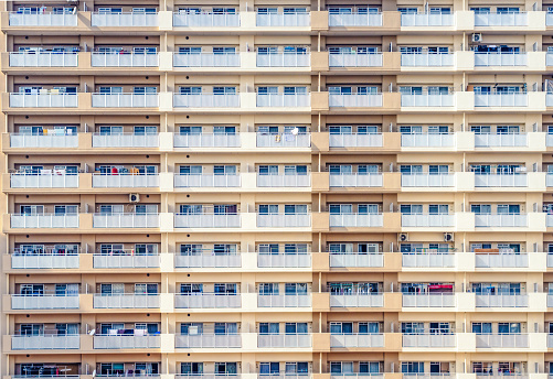 Multiple balconies in rows on the outside of a large apartment block in Japan.