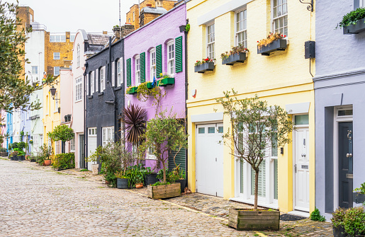 A row of painted mews houses on a cobbled street in Kensington, London.
